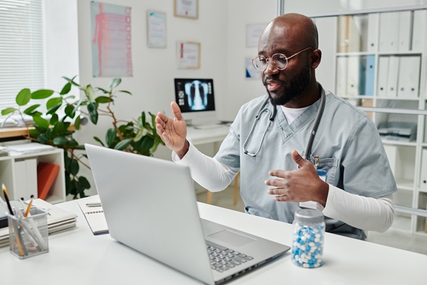 Young confident online doctor in uniform giving medical advice to patient