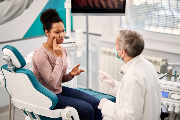 African American woman complaining about toothache to her dentist at dental clinic.