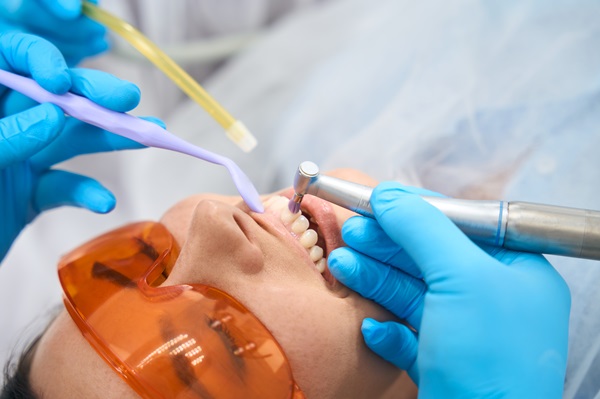 Dentist with the help of an assistant fills patients tooth